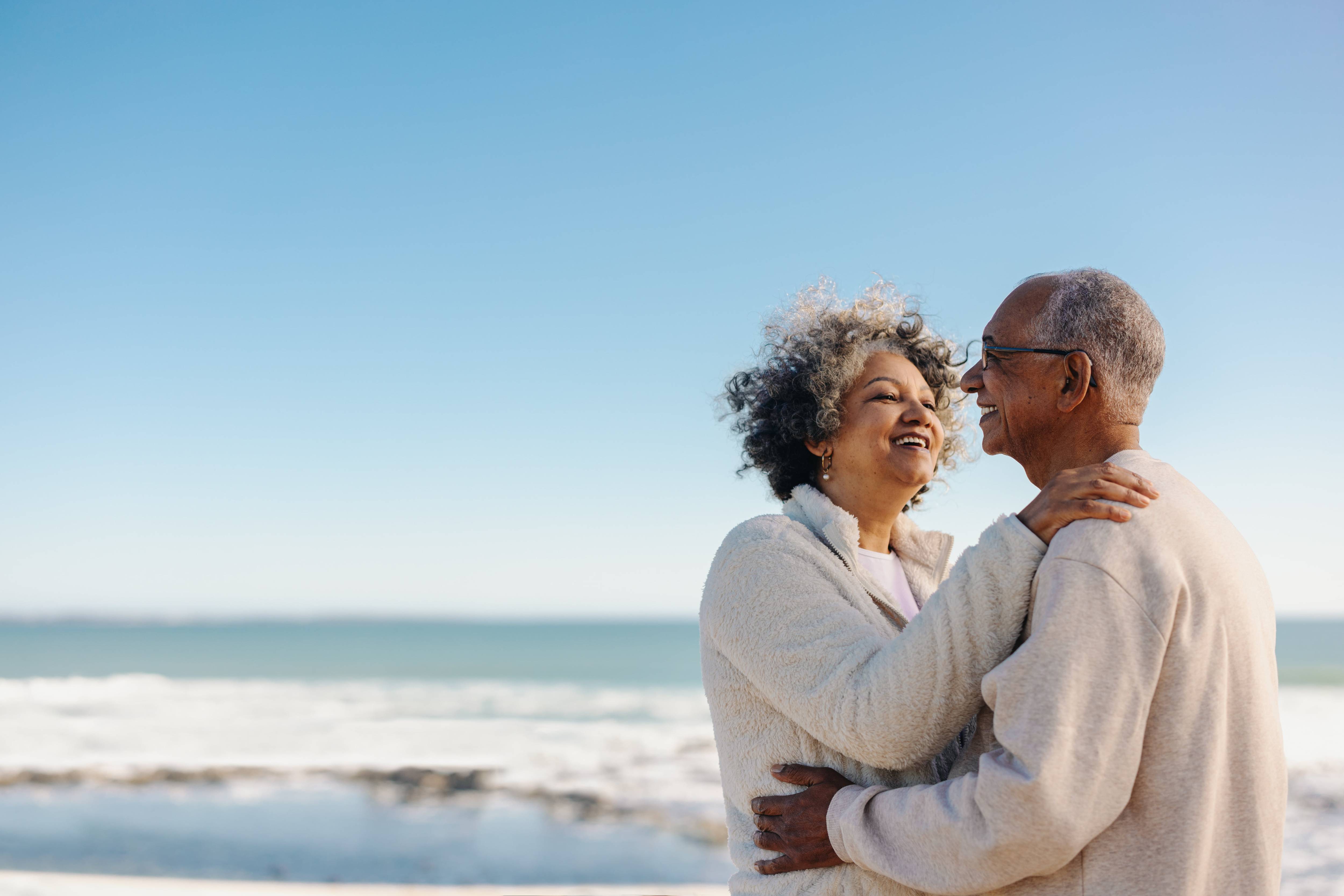 Stock photo of older couple holding each other at the beach